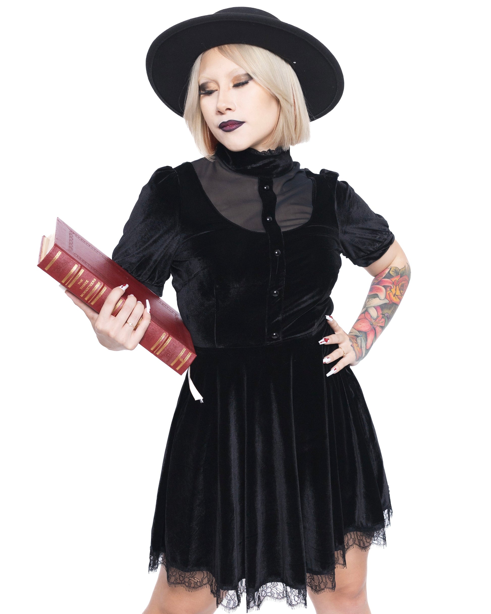Woman wearing short sleeve gothic dress for women by Olivia Noire Fashion holding a book and wearing a black hat